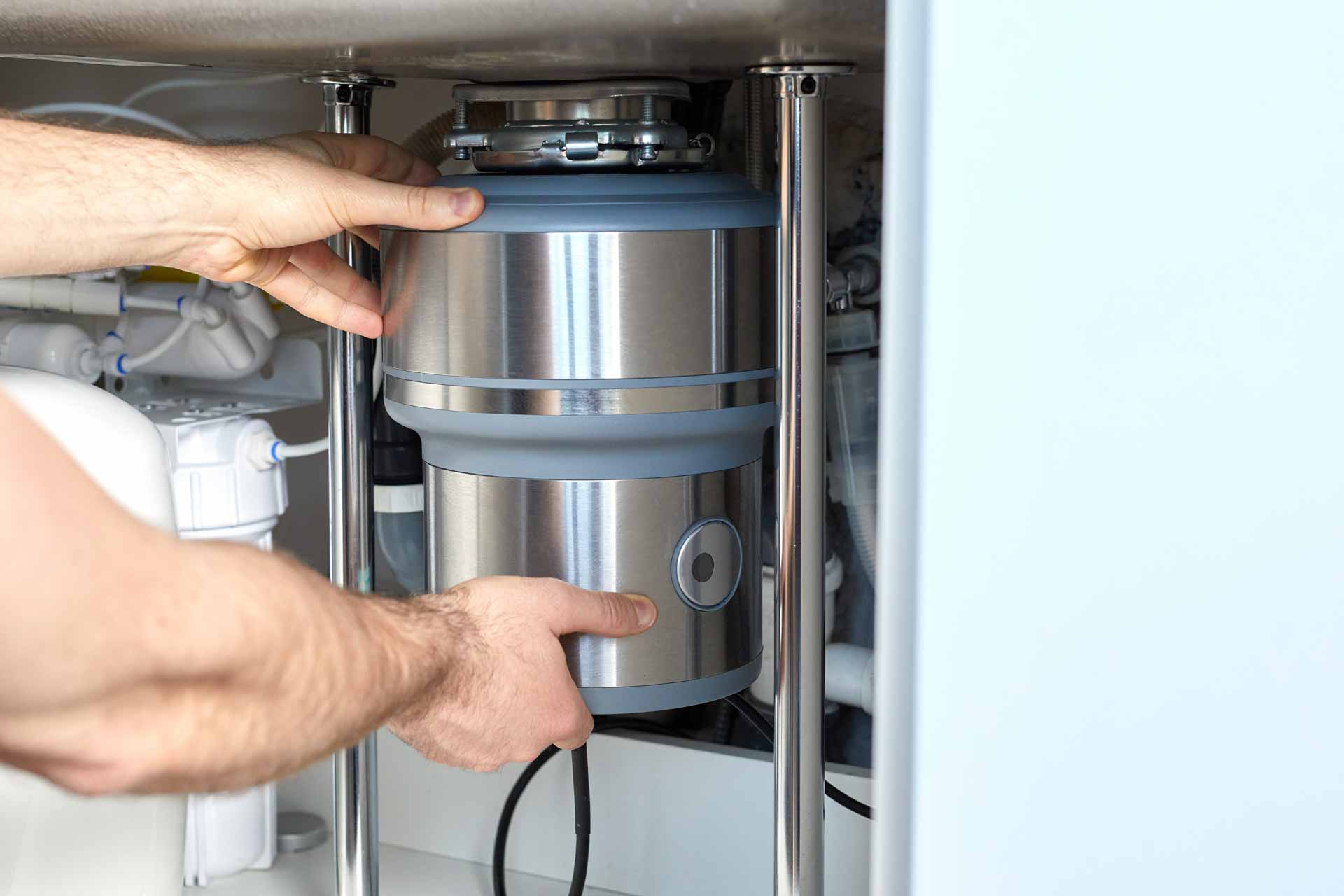 Appliance repair technician installing garbage disposal under sink